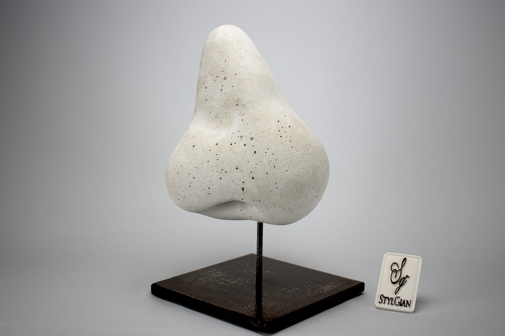sculpture d'un nez en béton blanc sur un socle en acier.