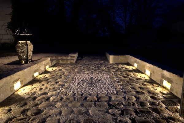 mosaîque en pierres vue de nuit avec éclairage, intégrant une fleur de lys noir en basalte.