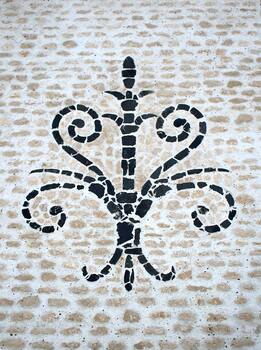 Image montrant une mosaîque en pierres, intégrant une fleur de lys noir en basalte sur un fond de pierres calcaire beige.